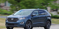 A blue ford edge driving down the street.