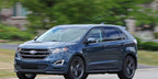 A blue ford edge driving down the street.